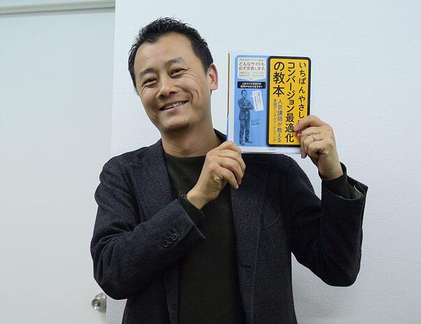 写真：再度著作を掲げる笑顔の深田。